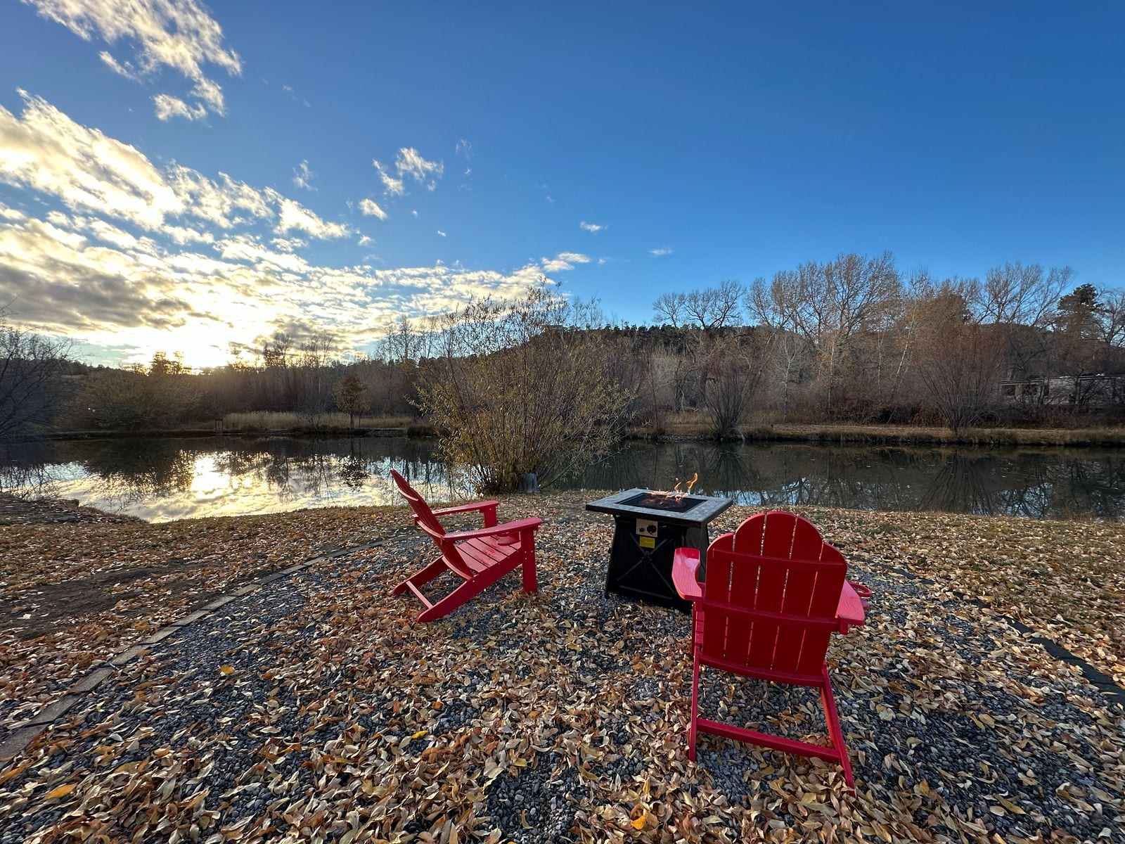 Fire pit and adirondack chairs by the pond at sunset