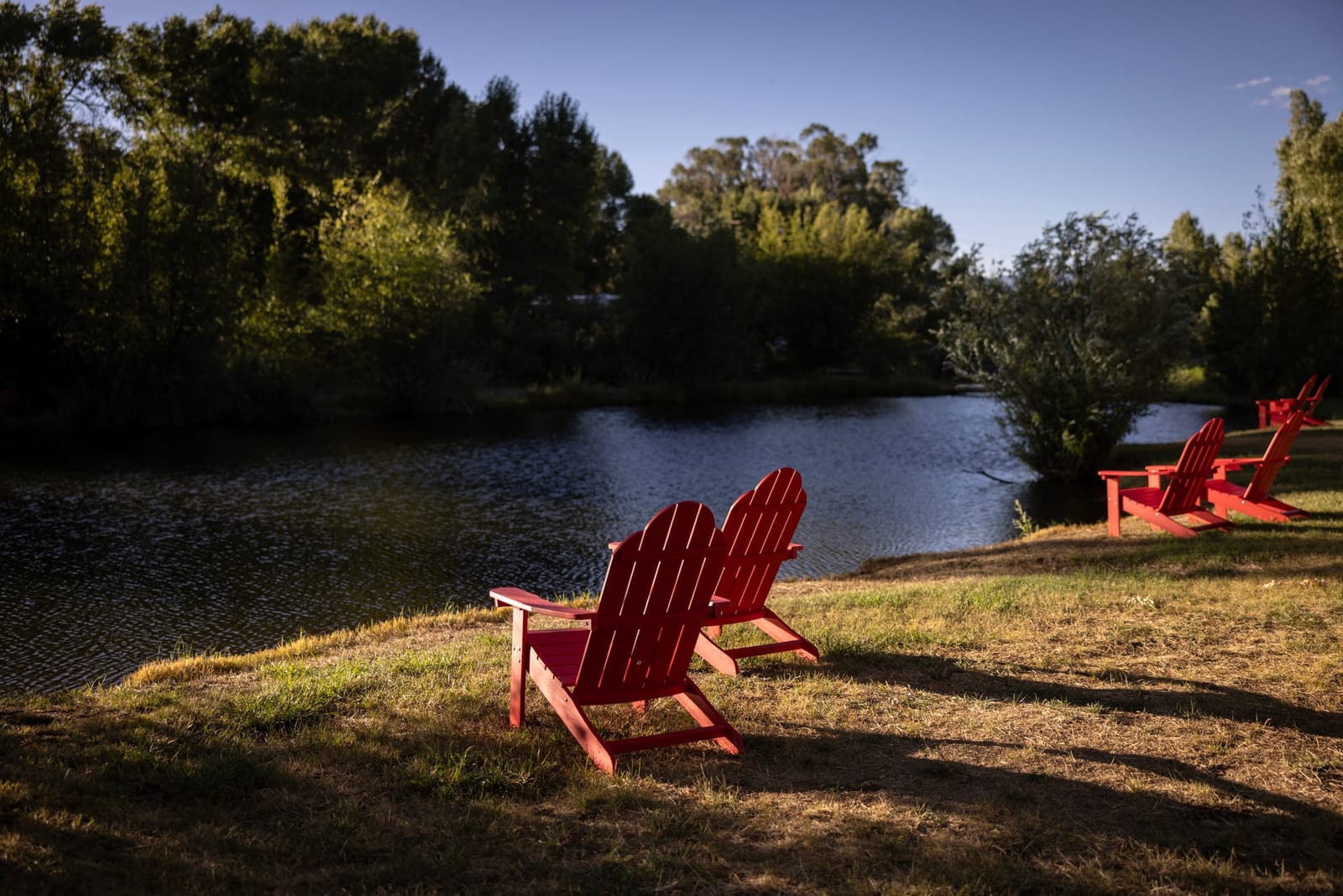 Adirondack chairs by the pond at sunset at Outdoorsy Bayfield