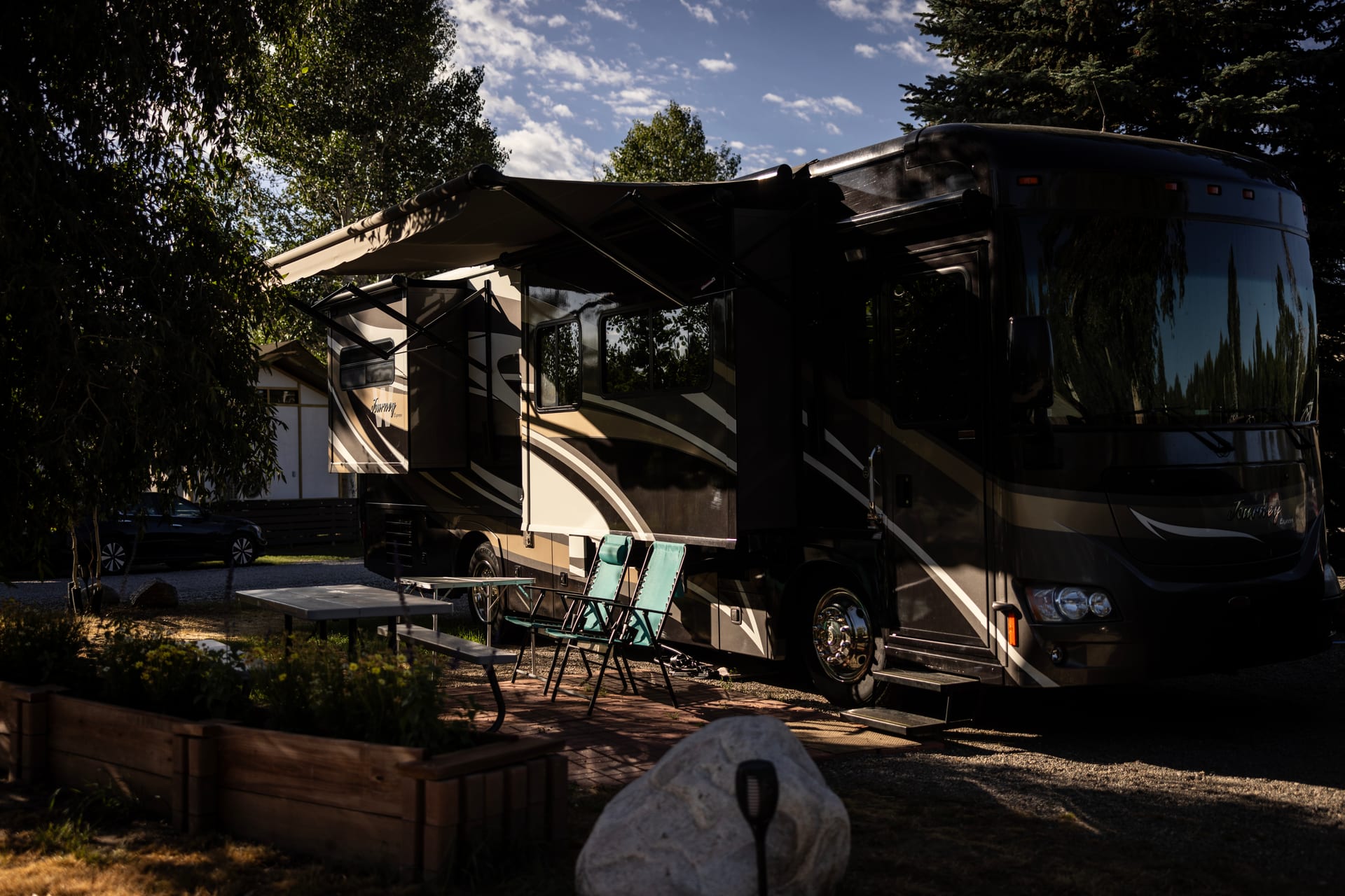 Class A motorhome parked at a pull-through site at Outdoorsy Bayfield with camp chairs and a table set up